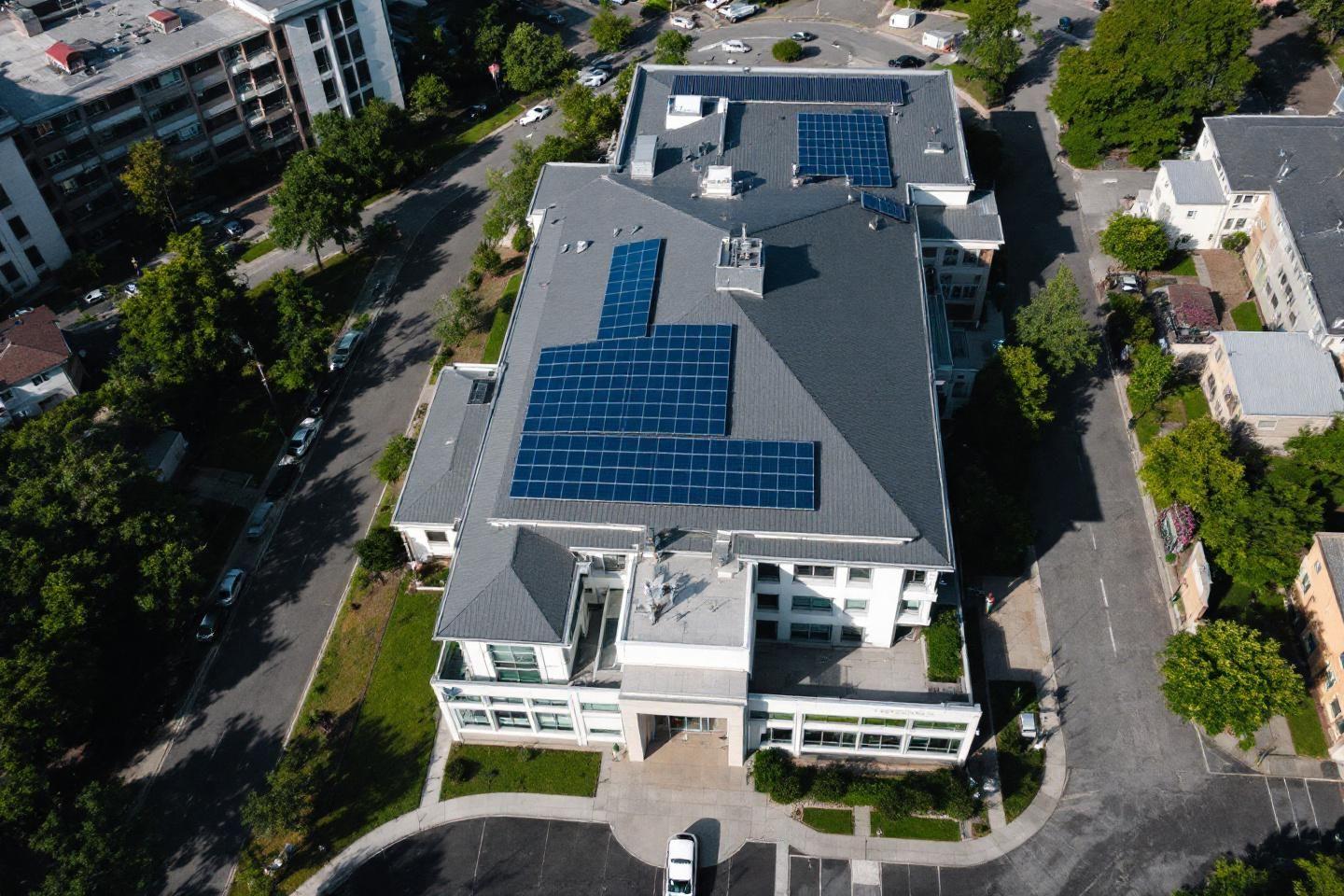 Vue aérienne d'un immeuble blanc avec toits équipés de panneaux solaires bleus