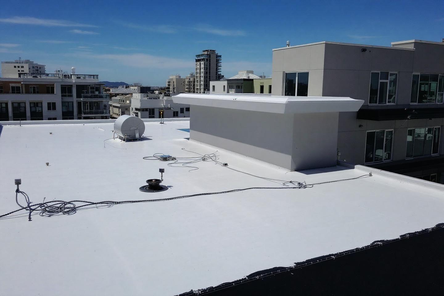 Toit blanc avec équipements techniques et vue sur immeubles