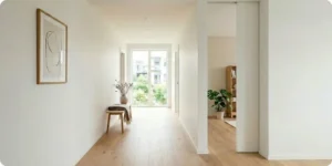 Porte a galandage entrouverte dans un couloir d'appartement renove, murs blancs et parquet chene clair