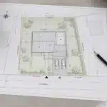 Plan de masse PCMI 2 sur table de travail avec règle et crayon pour permis de construire