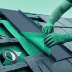 Ouvrier installant une membrane d'étanchéité et une plaque métallique sur une toiture en pente.