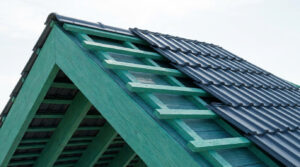 Structure de toiture en bois vert avec liteaux supportant des tôles imitation tuile gris anthracite.