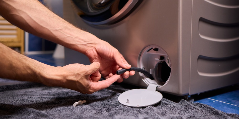 Petit tuyau de vidange d'urgence sorti sous la trappe du filtre d'un lave-linge, pour vider l'eau avant d'ouvrir le filtre
