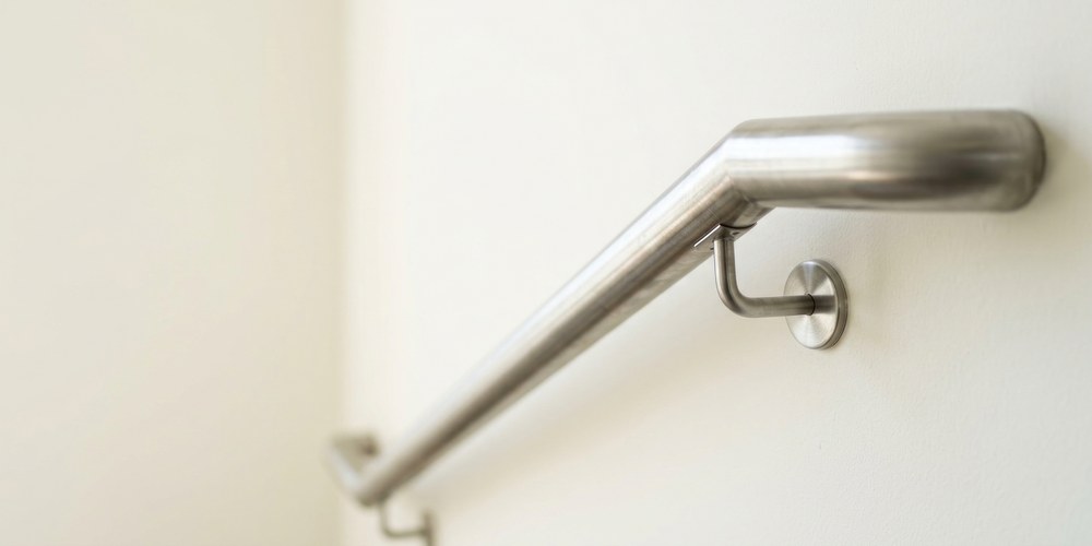 Main courante d'escalier en inox fixée au mur par une console, terminée par un prolongement horizontal