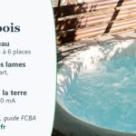 Spa gonflable rempli, entouré d'un pare-vue en lames de bois, sur une terrasse de jardin